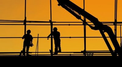 two people standing on scaffolding against a yellow sky