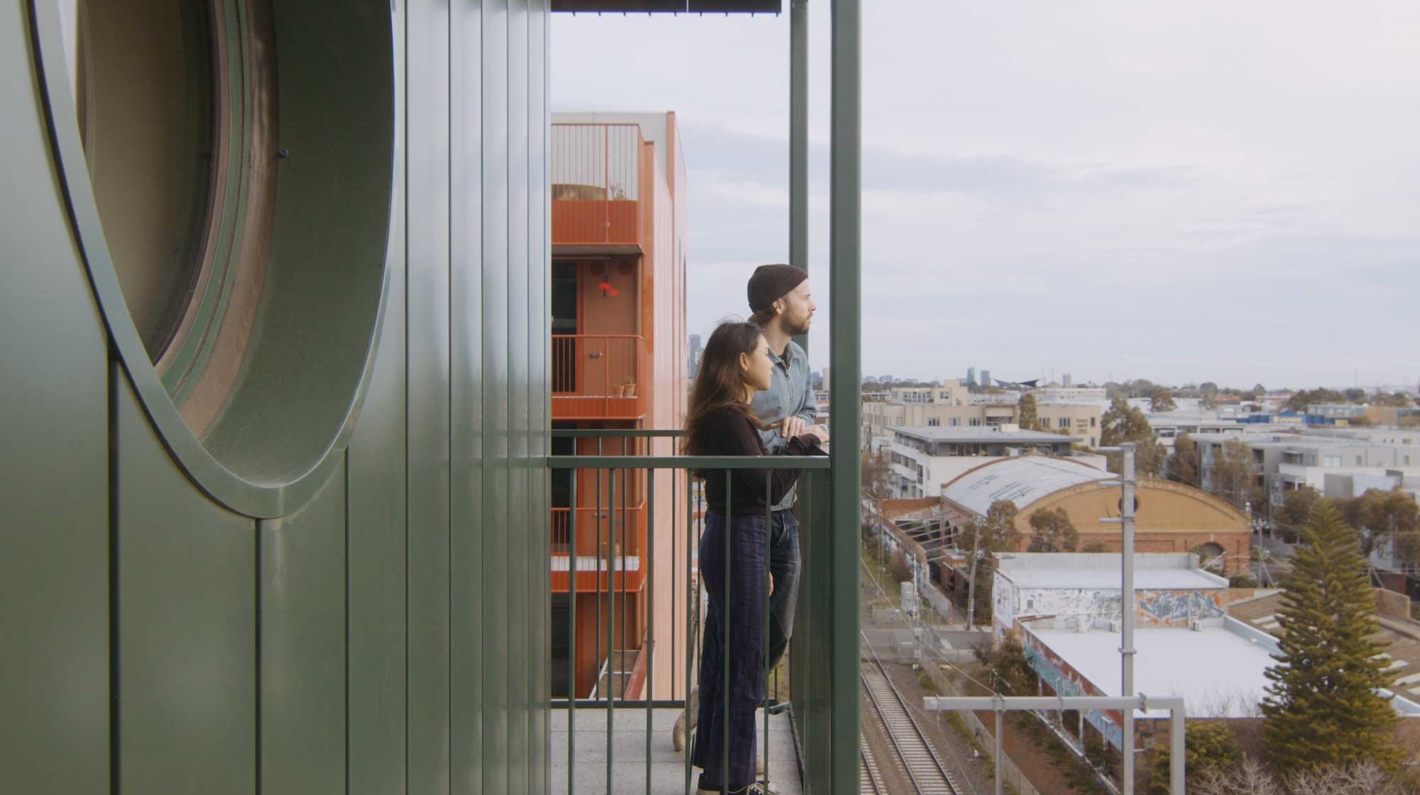 A couple looking off balcony from apartment