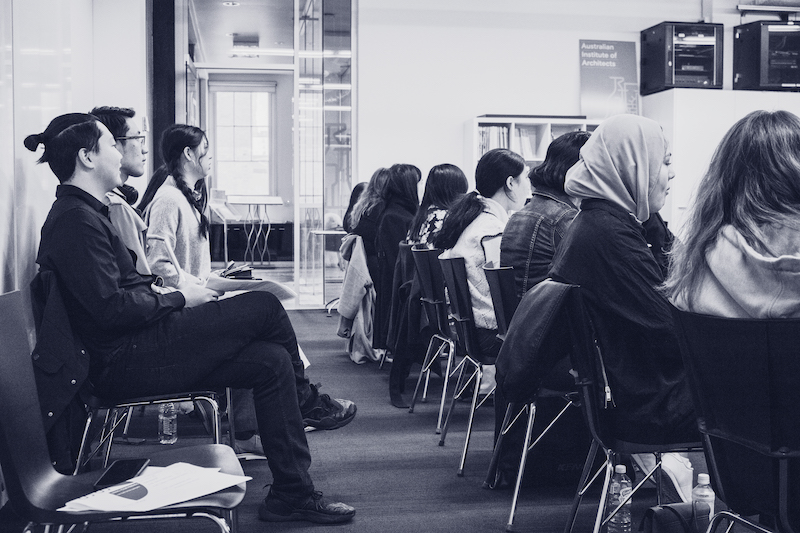two rows of people sitting in chairs listening to a talk