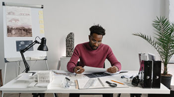 man at desk with architecture plans and models