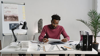 man at desk with architecture plans and models